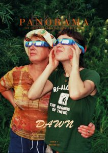 Two individuals stand closely together outdoors, looking up at the sky while wearing eclipse glasses.